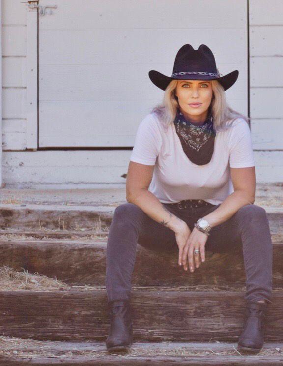 Ashlee seated on wooden steps in a black hat