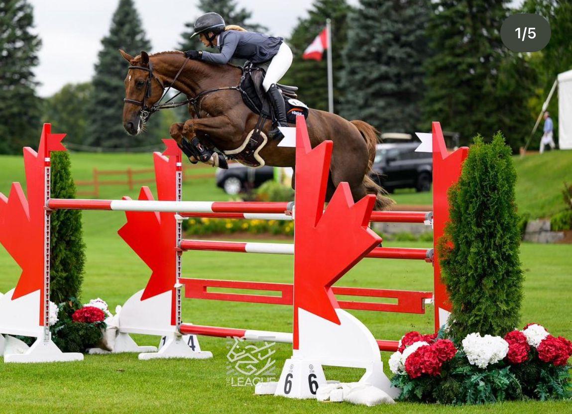 Ashlee jumping a red and white maple leaf fence