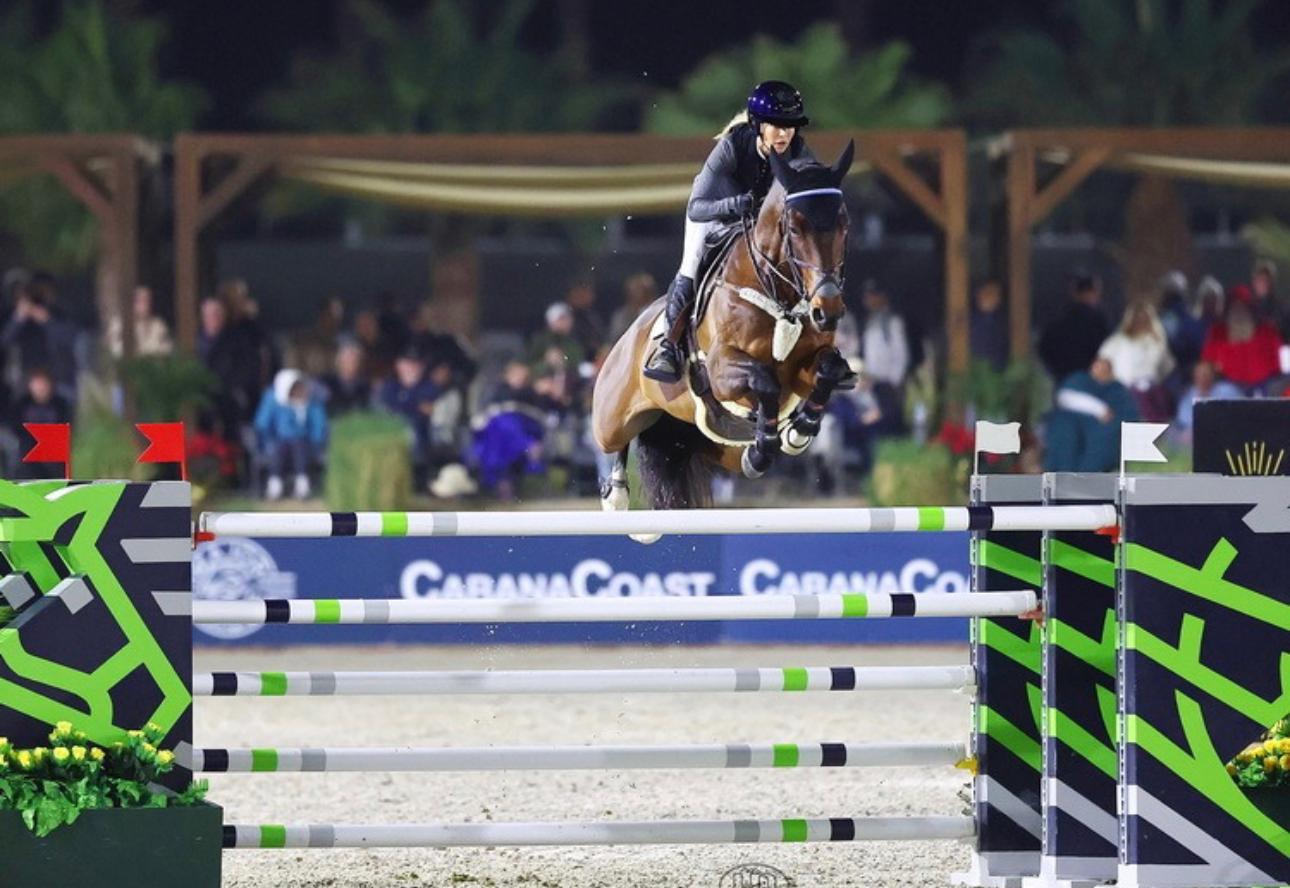Ashlee jumping green and black rails under the lights