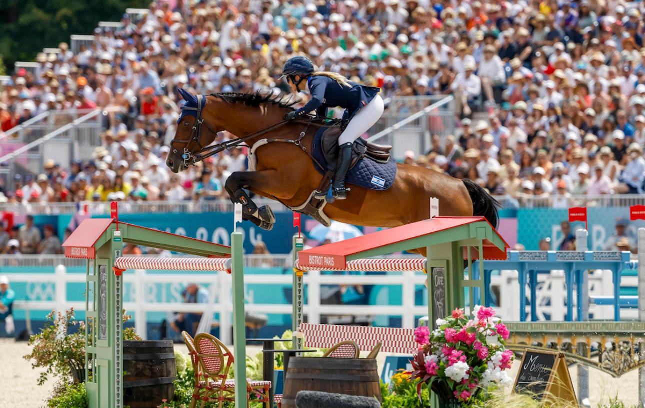 Ashlee and her bay horse clearing a jump in Paris